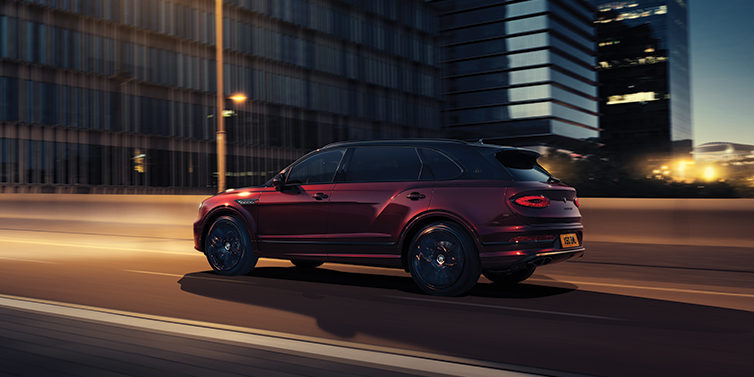Bentley Taichung Bentley Bentayga Extended Wheelbase Mulliner SUV in Cricket Ball red paint driving dynamically in city at night